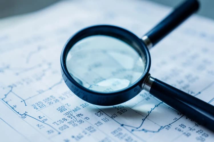 Lupa examinando um documento com gráficos e números