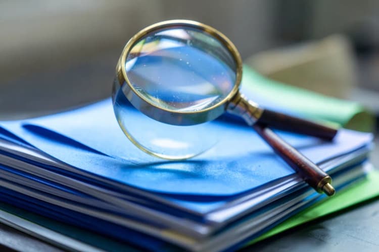 Documentos fiscais e uma lupa sobre eles, simbolizando a revisão.