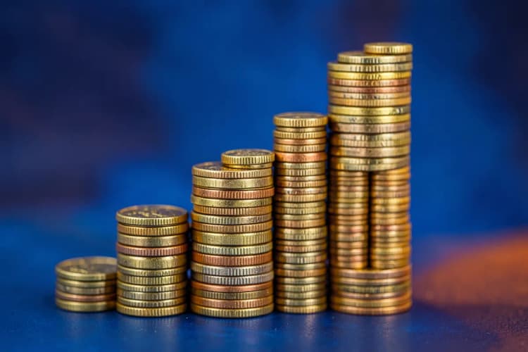 Gráfico de barras ascendente com moedas empilhadas ao lado, simbolizando crescimento financeiro.