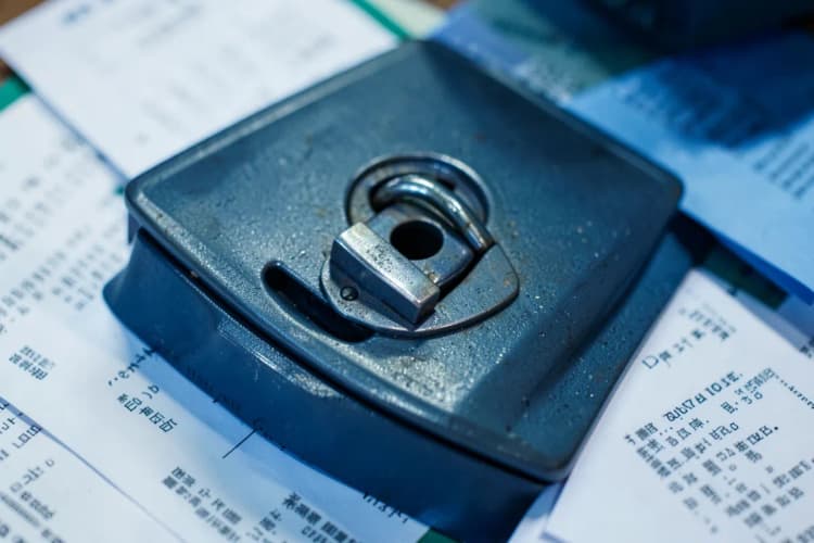 Um cofre de metal com um cadeado fechado, cercado por documentos e papéis.