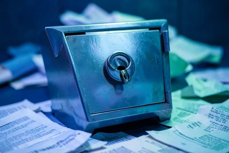 Um cofre de metal com um cadeado fechado, cercado por documentos e papéis.