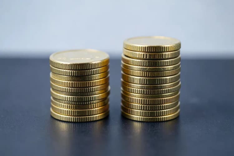 Duas pilhas de moedas de ouro, uma maior que a outra, representando valores diferentes.