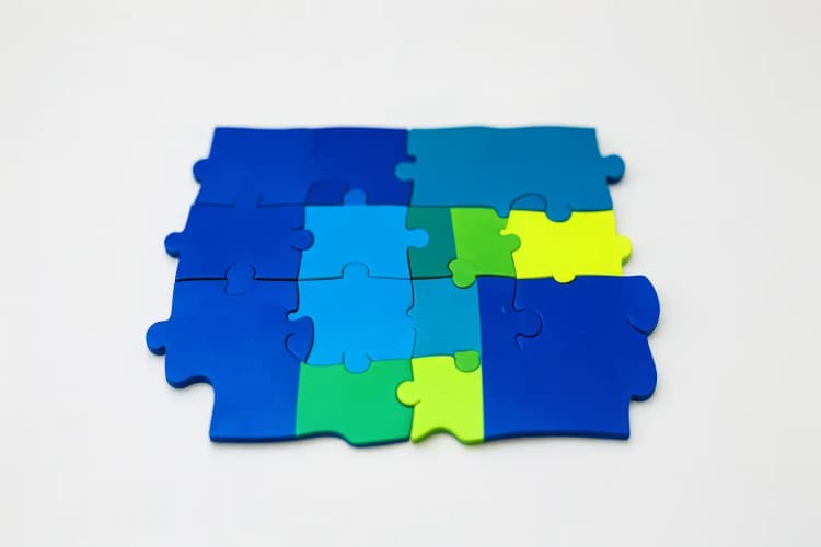 Peças de quebra-cabeça de cores diferentes se encaixando parcialmente, com algumas peças faltando.