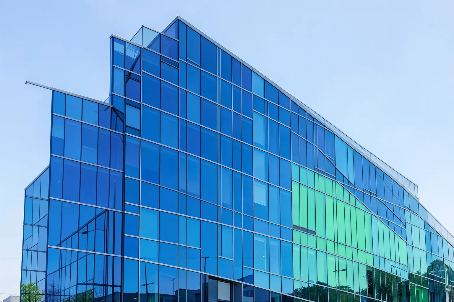Fachada de prédio de escritórios com arquitetura moderna e envidraçada, sob um céu azul claro.